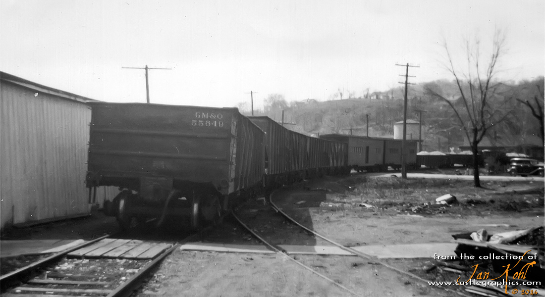 Freight on the transfer track, Louisiana, MO
Several gondolas and what appears to be some WWII ex-troop kitchen cars (now express baggage) being transferred between the CB&Q and GM&O.  Stark Bros Nursery used the express baggage cars to haul fruit trees.  This view is looking south towards the GM&O station (water tower is at right-center).
