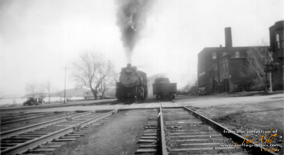 CB&Q Mikado in the railyard at Louisiana, MO.
A CB&Q Mikado steams up while a gondola sits on what the crews dubbed the "city" track.  The city track was owned by the GM&O and was used for transferring cars between the CB&Q and GM&O.  This view is looking south, notice the GM&O Mississippi river bridge to the left, and the automobiles sitting near the river.  The building at the left of the photo next to the river was a fresh fish market, still operating in the 1970s.   Thanks again to Archie Hayden for all the info.

