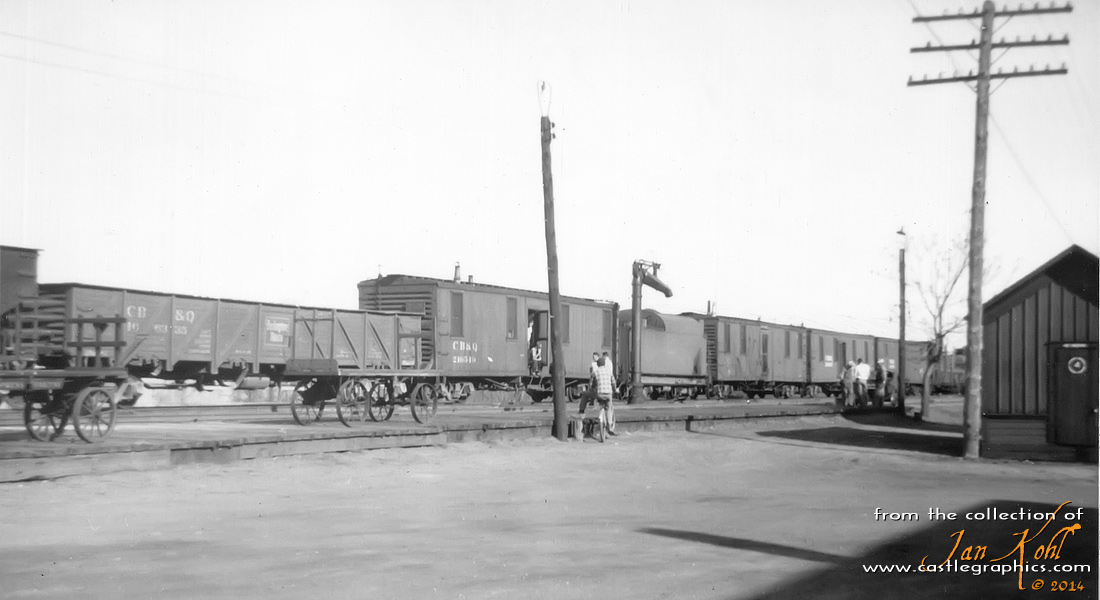 CB&Q work train, Louisiana, MO.
A Q work train sits in the yard at Louisiana, MO, while some railway workers hang out in the late afternoon.  Back in the day, work crews had their entire family come with them to a job, they all lived in the cars.  This work train consisted of a lot of heavily modified old boxcars as living accommodation.
